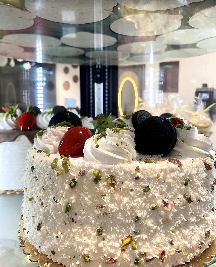 Weiße Torte mit Kirschen, Pistazien und Keks dekoriert